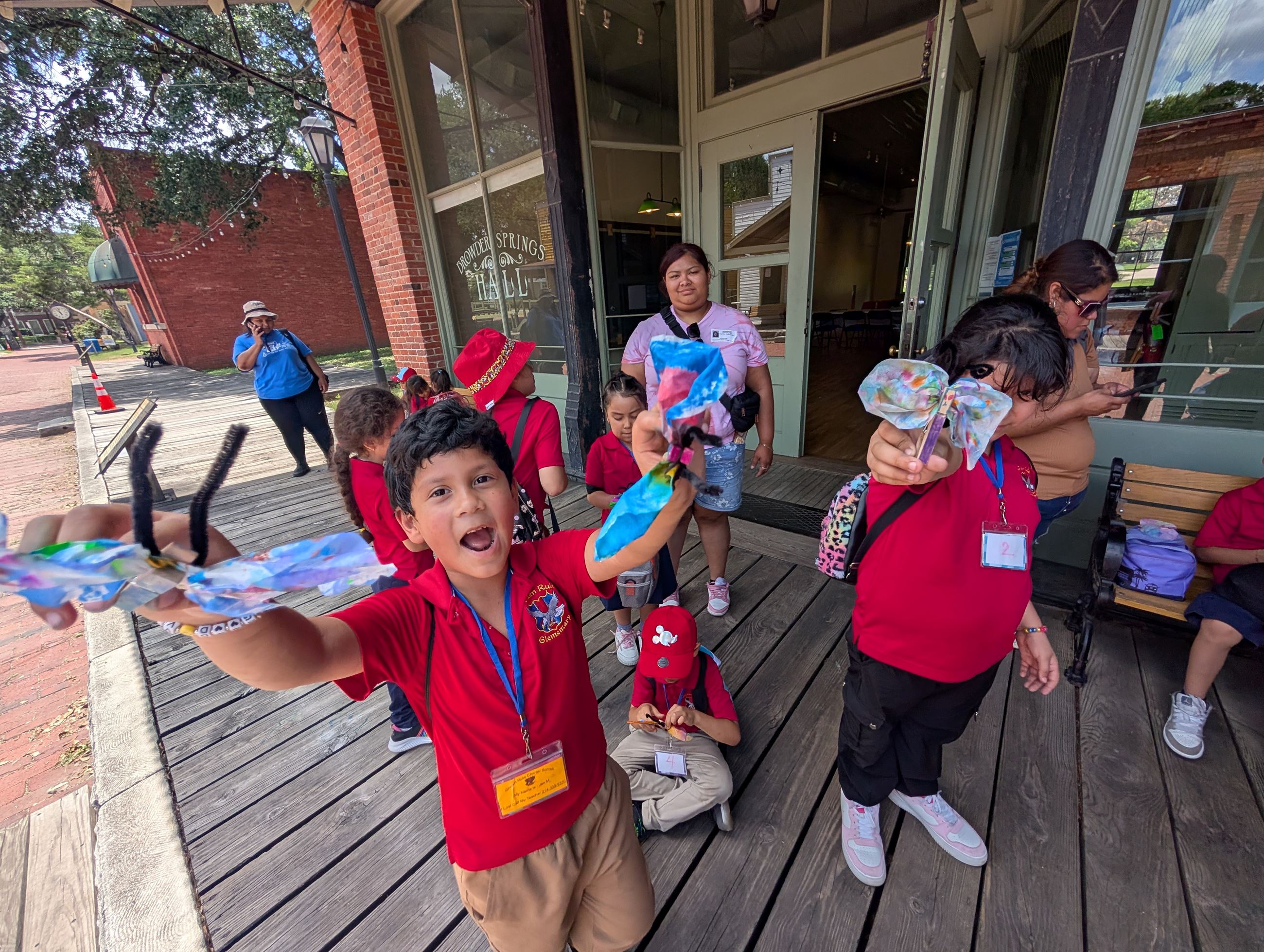 Picture of students on a field trip holding butterfly crafts